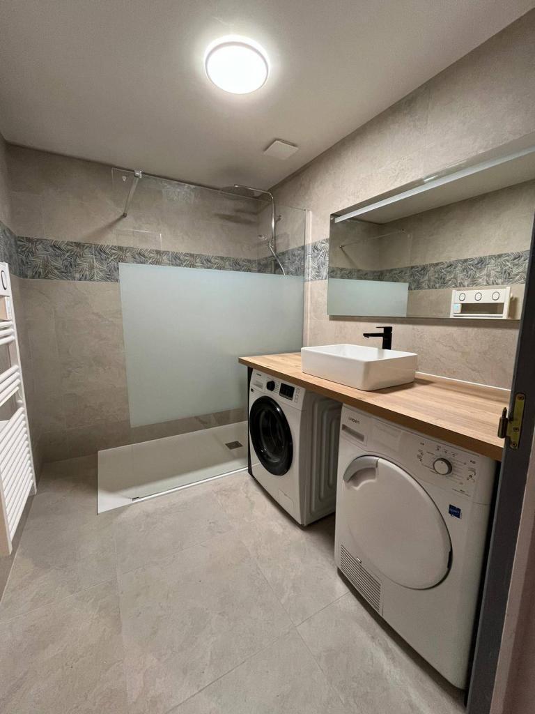 Vue d'ensemble d'une salle de bain rénovée avec douche, lavabo et équipements sanitaires